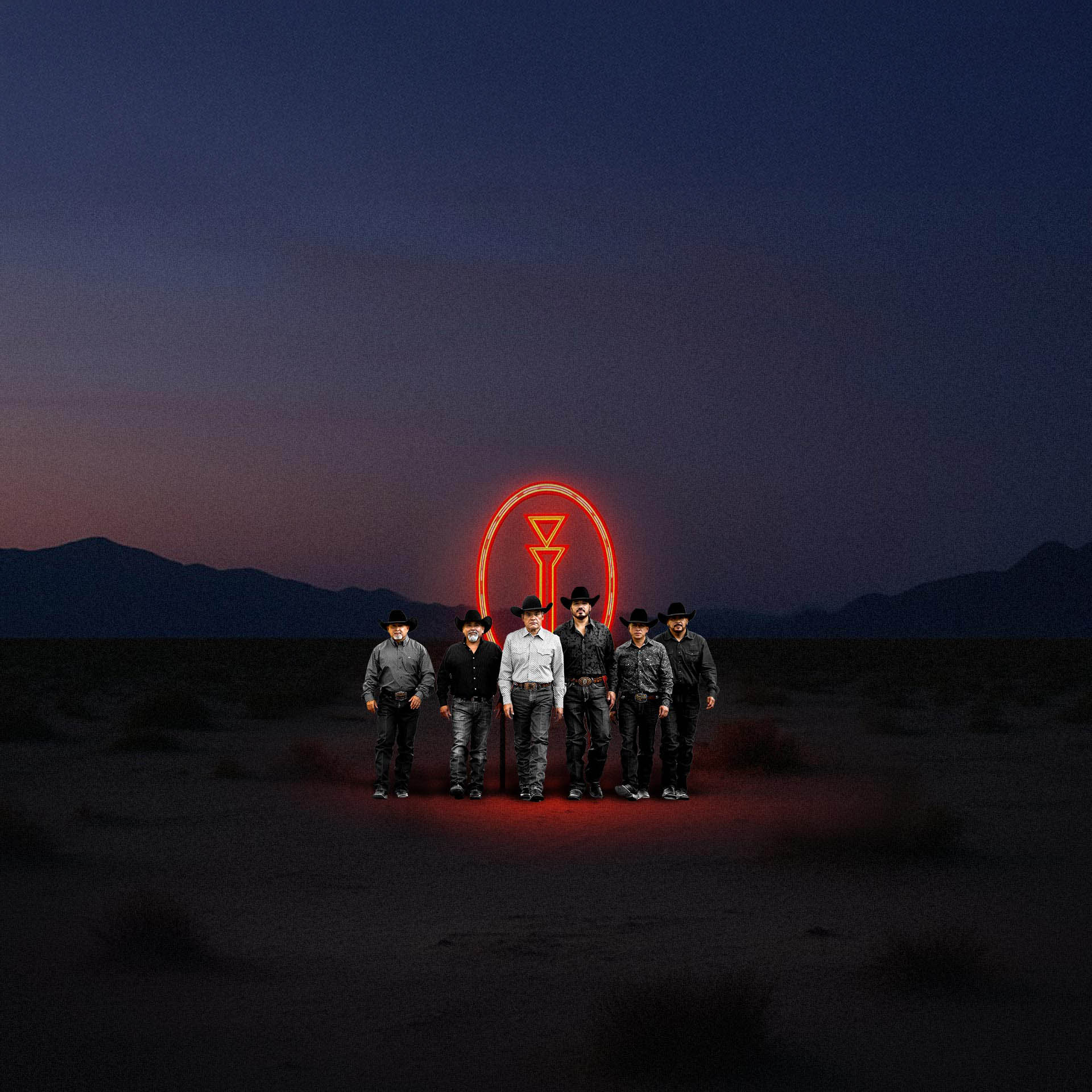Photo of the band standing in the desert in front of a glowing band logo
